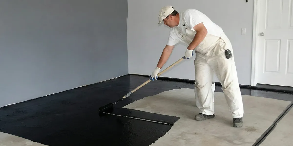basement waterproofing professional applying waterproof coating to protect a basement floor in Seattle, WA